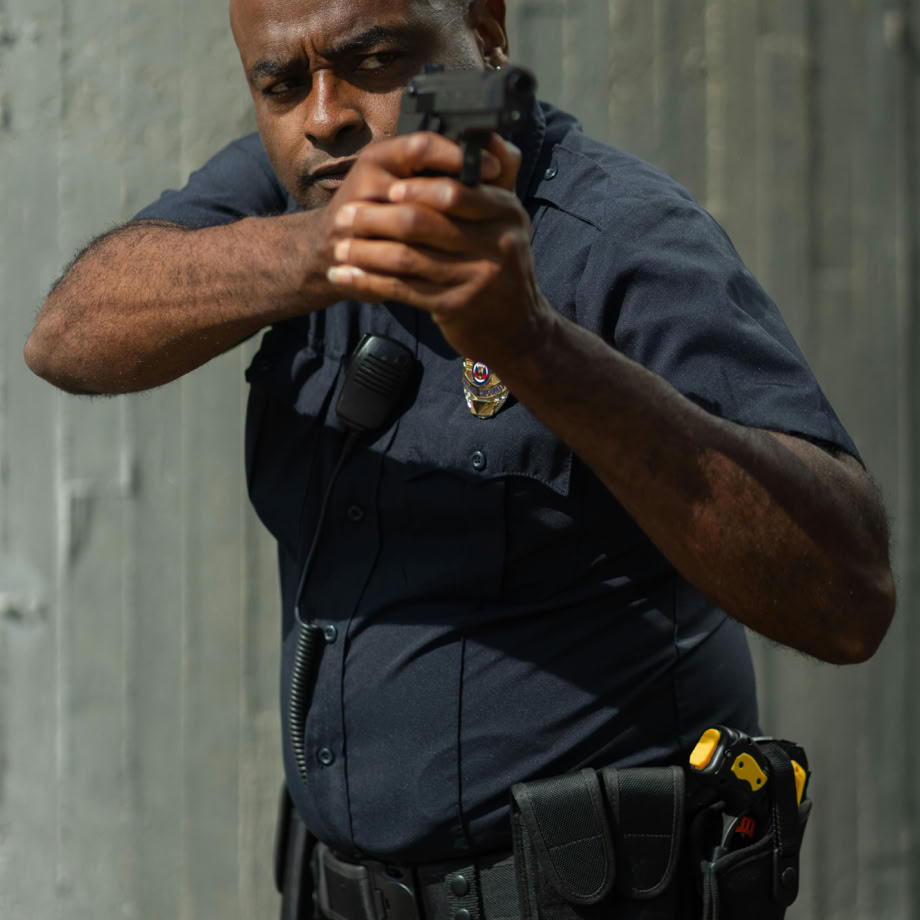 A determined police officer in uniform, aiming a firearm on duty, ensuring public safety.