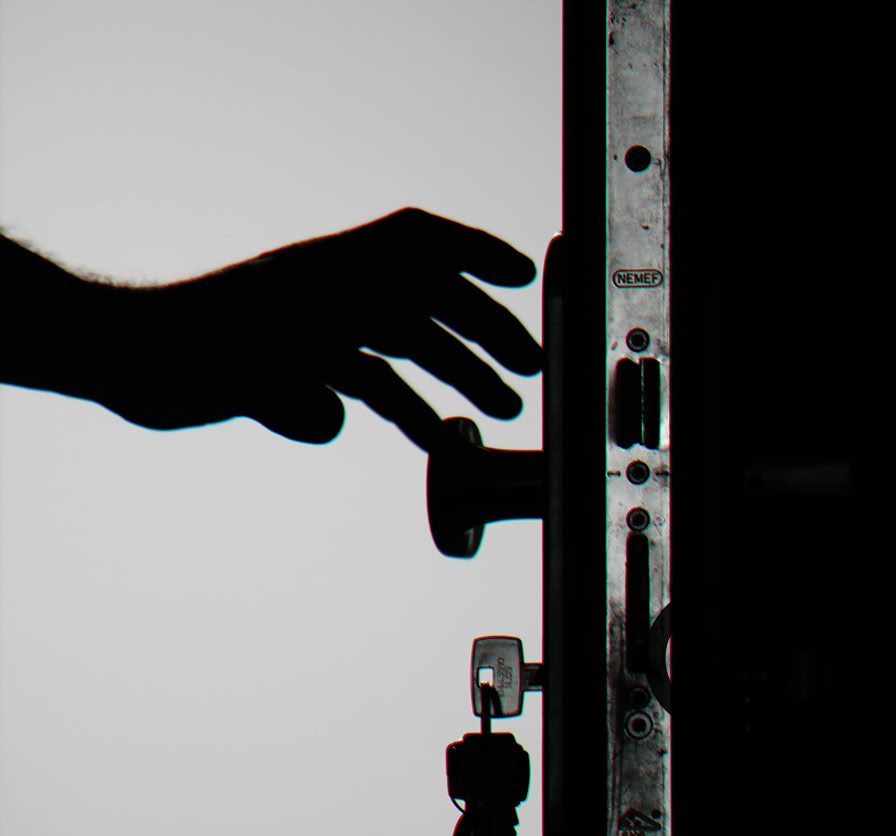 Silhouette of a hand about to open a door with keys in lock, symbolizing security.